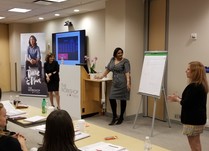 Three women presenting information on an easel pad to conference attendees 
