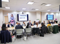 Conference attendees speaking to each other while sitting around a long table