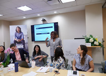 Woman presenting to conference attendees sitting around a long table