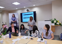 Woman presenting to conference attendees sitting around a long table