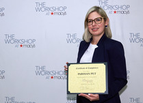 Parisian Pet with a Certificate of Completion in front of a "The Workshop at Macy's" backdrop