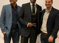 Three men posing for a photo in front of The Workshop at Macy's banner
