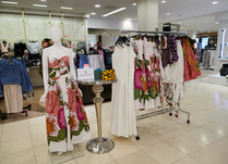 Mannequin dressed in a floral dress and a clothing rack in an aisle