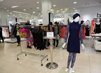 Mannequin dressed in blue and a clothing rack in an aisle