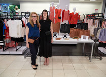 Two women proudly standing in front of a product table with bags