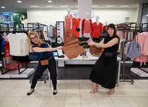Two women pretend to be fighting over a bag