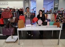 Two women proudly standing behind Gunas New York product table