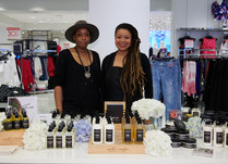 Two women proudly standing behind Earth's Nectar hair care product table