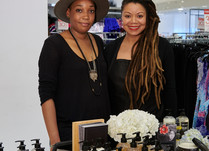 Two women standing behind Earth's Nectar hair care product table