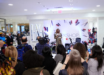 Woman on stage with microphone addressing attendee audience