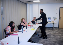 Man presenting to individuals sitting around a table