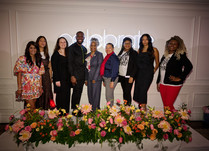 Group of 9 people standing in front of a celebrate neon sign