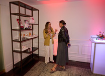 Two women talking by a shelf with products