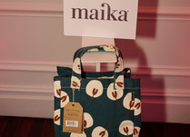 A printed bag with a sign above that says Maika