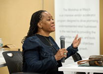 A female attendee with a microphone addresses the other workshop attendees