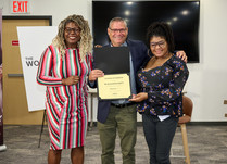 A man presenting two women with a Black Paper Party Certificate of Completion