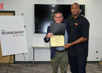 A man presenting a man with a Kyvan Certificate of Completion
