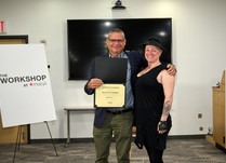 A man presenting a woman with a Play Out Apparel Certificate of Completion