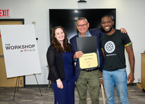 A man presenting two people with a True Moringa Certificate of Completion