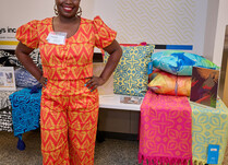 A woman standing in front of a table with brightly colored fabric products