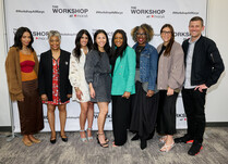 A group of 8 people stand in front of The Workshop at Macy's banner