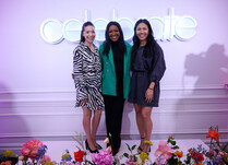A group of 3 women pictured in front of a "celebrate" neon sign