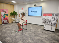 A woman with a microphone addresses the workshop attendees from behind a podium