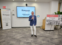 A man with a microphone speaks to workshop attendees