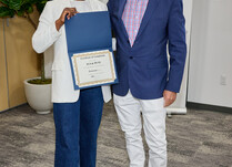 A man presenting a woman with an Aya and Pete Certificate of Completion