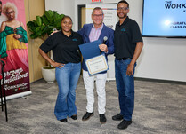 A man presenting two people with a Certificate of Completion