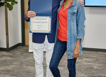 A man presenting a woman with a Bea's Bayou Skincare Certificate of Completion