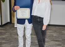 A man presenting a woman with a DefineMe Certificate of Completion