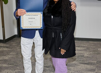 A man presenting a woman with a DomoInk Certificate of Completion