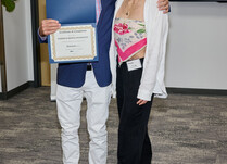 A man presenting a woman with a Goddess Rising Intimates Certificate of Completion