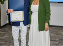 A man presenting a woman with a Maple Organics Certificate of Completion
