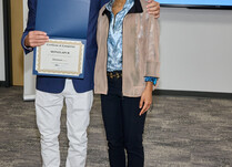 A man presenting a woman with a Monzlapur Certificate of Completion