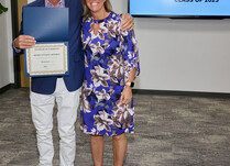 A man presenting a woman with a Certificate of Completion