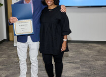 A man presenting a woman with a Ms. Jetsetter Certificate of Completion