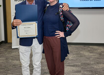 A man presenting a woman with a Po Campo Certificate of Completion