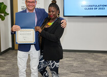 A man presenting a woman with a Rochelle Porter Certificate of Completion