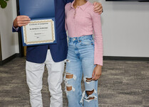 A man presenting a woman with a Surprise Powerz Certificate of Completion
