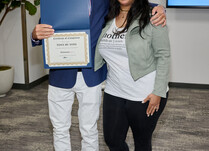 A man presenting a woman with a Tony by Toni Certificate of Completion