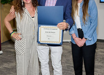A man presenting two women with a Wax Buffalo Certificate of Completion