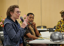 A woman with a microphone addresses the workshop attendees