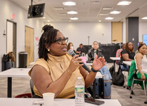 A workshop attendee with a microphone speaks during the workshop