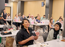 A workshop attendee with a microphone speaks during the workshop