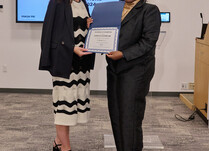 A woman presenting another woman with a Certificate of Completion