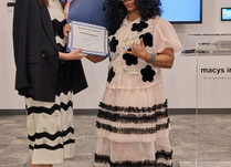 A woman presenting another woman with a Coradorables Certificate of Completion