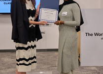 A woman presenting another woman with a Flora and Noor Certificate of Completion