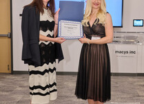 A woman presenting another woman with a Certificate of Completion